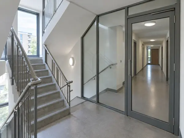 Concrete stairwell with a glazed screen and glazed lobby door leading to a corridor